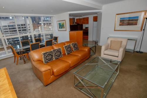 a living room with a leather couch and a glass table at Bond 1603 Self Catering in Sydney
