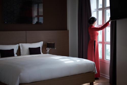 a woman in a red dress looking out of a window at Mercure Hanoi La Gare Hotel in Hanoi