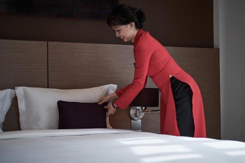 a woman is standing next to a bed at Mercure Hanoi La Gare Hotel in Hanoi