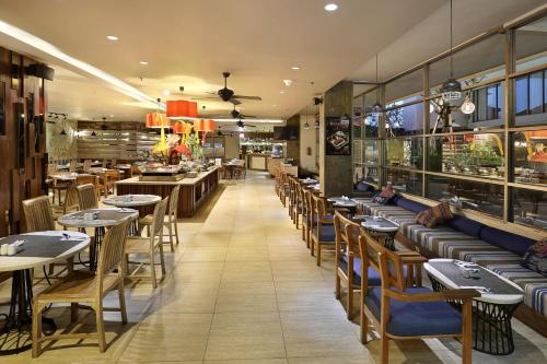 a restaurant with tables and chairs and a cafeteria at Harper Kuta Hotel by ASTON in Legian