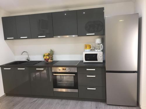 a kitchen with black cabinets and a white refrigerator at Sunflower in Kaštela