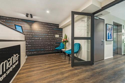 a waiting room with a table and blue chairs at Mantra One Sandy Bay Road in Hobart
