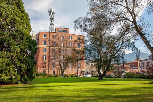 a large brick building in a field of grass at Mantra One Sandy Bay Road in Hobart