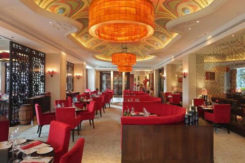 a restaurant with red chairs and tables and a chandelier at Shangri-La Jakarta in Jakarta