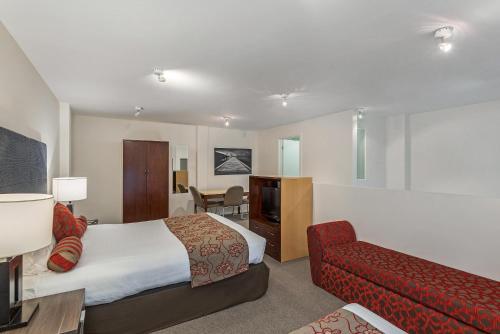 a hotel room with a bed and a red couch at Mantra One Sandy Bay Road in Hobart