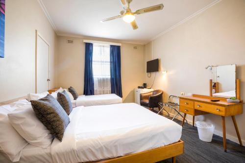 a hotel room with a bed and a desk and a desk at Esplanade Hotel Adelaide in Adelaide