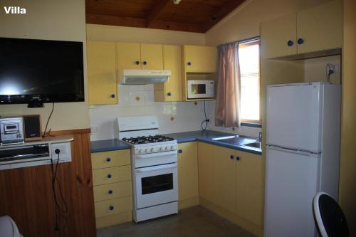 a kitchen with a white stove and a refrigerator at Lani's Holiday Island in Forster