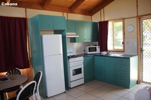 a kitchen with green cabinets and a white refrigerator at Lani's Holiday Island in Forster