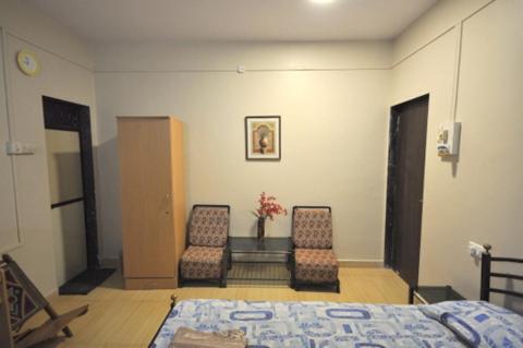 a bedroom with two chairs and a bed and a table at Shilaj in Dapoli