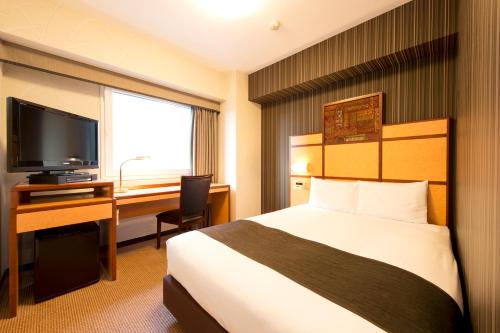 Cette chambre comprend un lit, un bureau et une télévision. dans l'établissement Hotel Villa Fontaine Tokyo-Hamamatsucho, à Tokyo