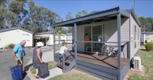 two people with luggage standing outside of a tiny house at BIG4 Moama Holiday Park in Moama