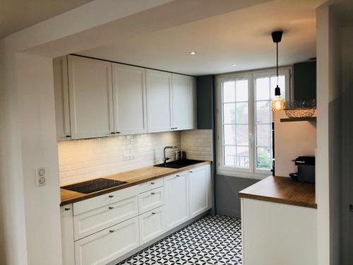 a kitchen with white cabinets and a black and white tile floor at Bel Appartement vue mer in Merville-Franceville-Plage