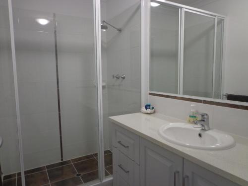 a white bathroom with a shower and a sink at The Beach Villa Bunbury in Bunbury