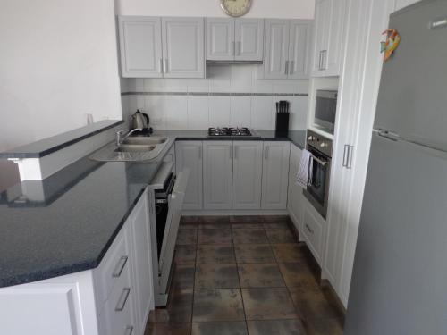 a kitchen with white cabinets and a tile floor at The Beach Villa Bunbury in Bunbury