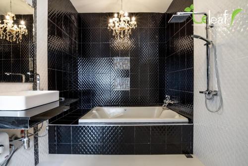 a black tiled bathroom with a tub and a sink at Le Leaf Valley Hua Hin 29 in Hua Hin