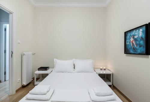 a white bedroom with a white bed and a tv at Kolonaki Square Apartment in Athens