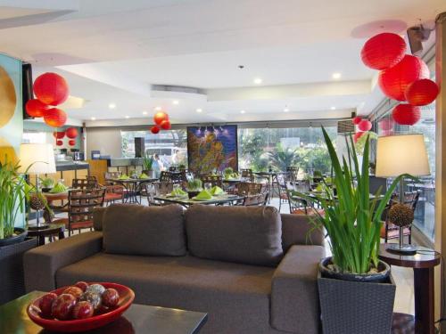 una sala de estar con sofá y mesas y un restaurante en The Corporate Inn Hotel en Manila