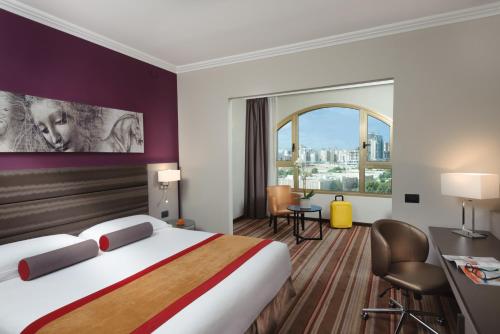 a hotel room with a bed and a large window at Leonardo Hotel Negev in Beer Sheva