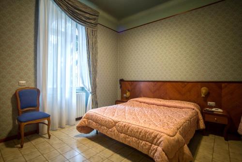 a bedroom with a bed and a chair and a window at Hotel Terme in Sarnano