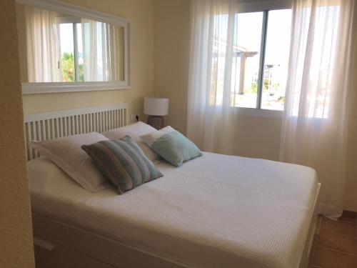 1 dormitorio con 1 cama blanca y 2 ventanas en Apartamento El Mirador de Vera playa, en Vera