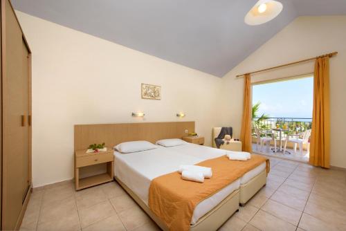 a bedroom with a large bed and a large window at Olympion Village in Kavos