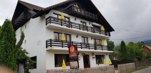 a white building with yellow flags in front of it at Pensiunea Casa Beatrice Bran in Bran