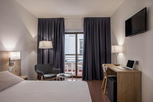 a hotel room with a bed and a desk with a laptop at Hotel Villa San Juan in San Juan de Alicante
