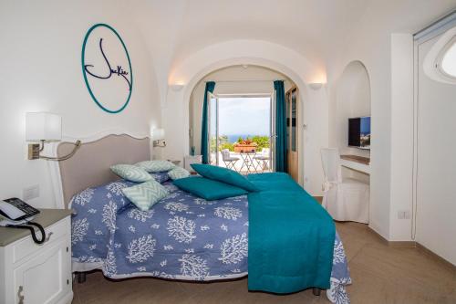 a bedroom with a bed with blue sheets and a balcony at Villa Patrizi in Capri