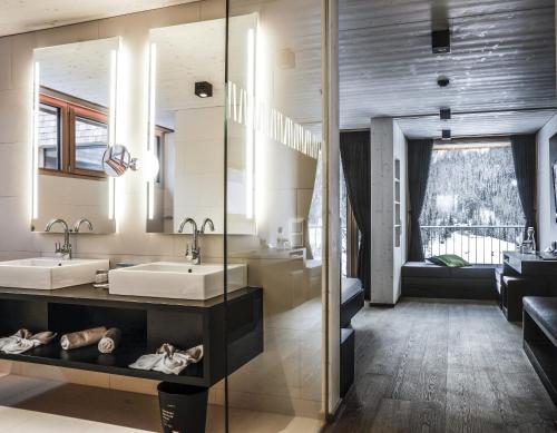 un bagno con due lavandini e un grande specchio di Gradonna Mountain Resort Chalets & Hotel a Kals am Grossglockner