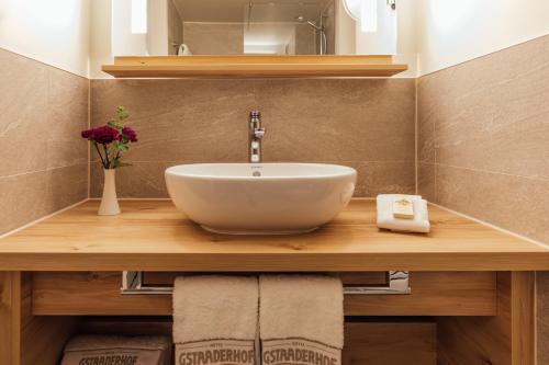 baño con lavabo blanco en una encimera de madera en Gstaaderhof - Active & Relax Hotel, en Gstaad