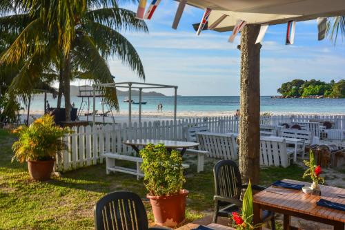 a beach with tables and chairs and the ocean at Berjaya Praslin Resort in Anse Volbert Village