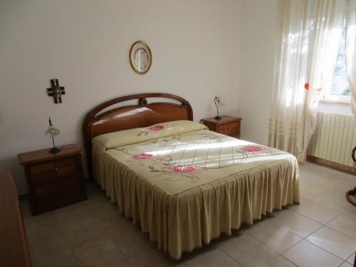 1 dormitorio con 1 cama y 1 cruz en la pared en Casa Dario, en Melissano