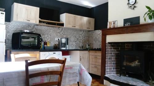 a kitchen with a fireplace and a microwave at La petite maison normande in Ticheville