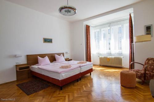 a bedroom with a bed and a chair and a window at Pension Karnet in Prague