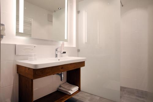 a white bathroom with a sink and a shower at Landgasthof Barenwirt in Petzenkirchen