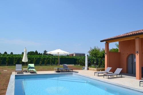 una piscina con sillas y sombrilla en Corte Reginella, en Roverbella