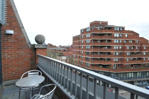 a balcony with a table and chairs and a building at Victoria One in London