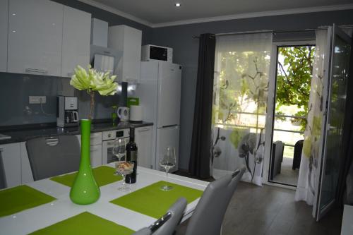 uma cozinha com uma mesa com um vaso verde com flores em Apartment D & N em Kaštela