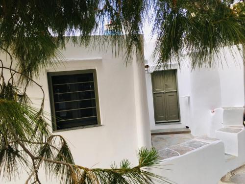 una casa blanca con una puerta verde y árboles en Iris house, en Apollonia