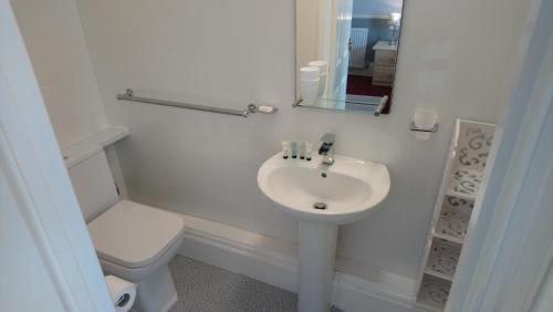 a white bathroom with a toilet and a sink at The Great Western B&B in Paignton