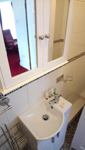 a bathroom with a white sink and a mirror at The Great Western B&B in Paignton