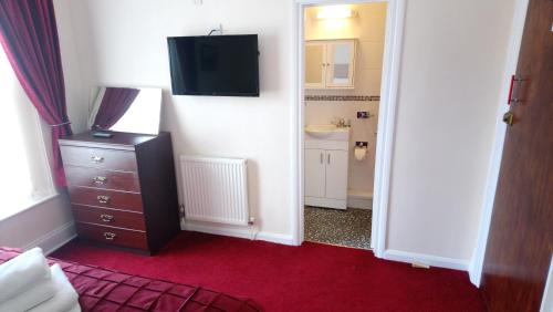 a bedroom with a dresser and a tv on the wall at The Great Western B&B in Paignton