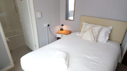 a small bedroom with a white bed and a mirror at The Great Western B&B in Paignton