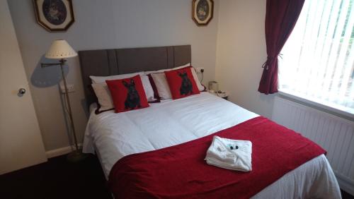 a bed with a red blanket and a white bag on it at The Great Western B&B in Paignton