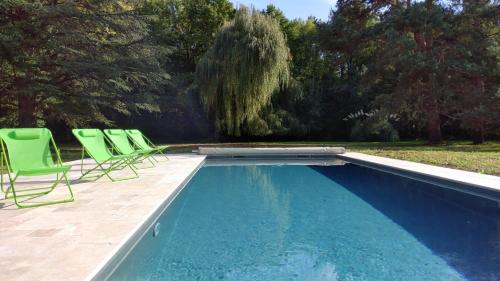 einen Pool mit grünen Stühlen neben einem Hof in der Unterkunft La Blinerie in Sambin