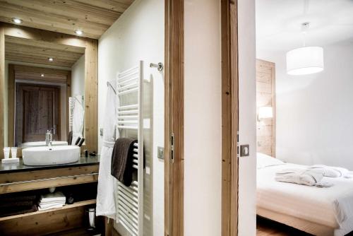 a bathroom with a sink and a bed and a mirror at Résidence - Les Grandes Alpes in La Clusaz