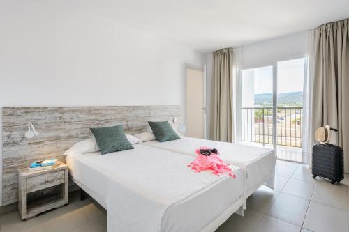 1 dormitorio con 1 cama blanca grande y ventana en Apartamentos Vibra Riviera en San Antonio Bay