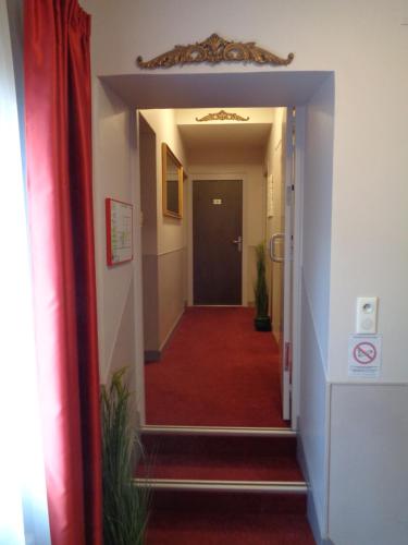 a hallway with a red carpet and a black door at Hotel de Montaulbain in Verdun