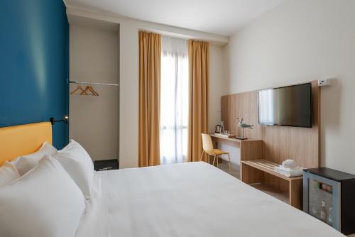 アラッシオにあるHotel Rivaの大きなベッドとデスクが備わるホテルルームです。