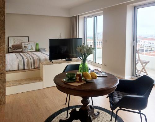 a living room with a table and a bed and a television at Studio 177 in Matosinhos